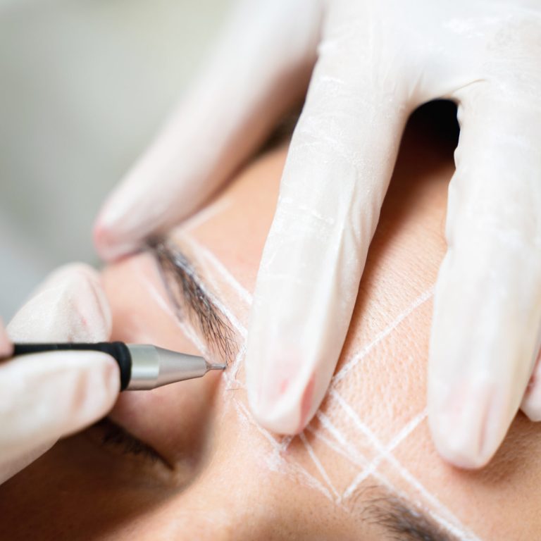 Young woman during professional eyebrow mapping procedure before permanent makeup